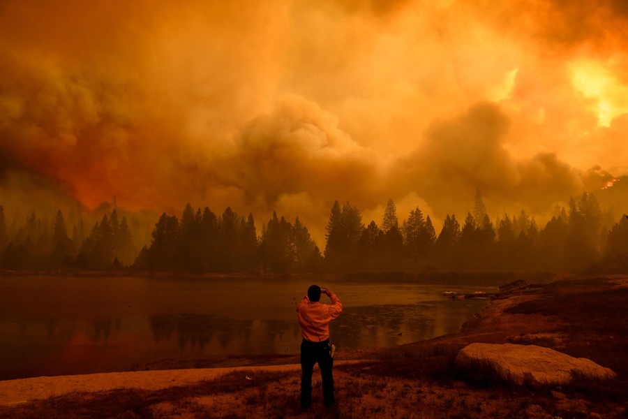 A person takes a photograph of the smoke from a forest fire nearby.