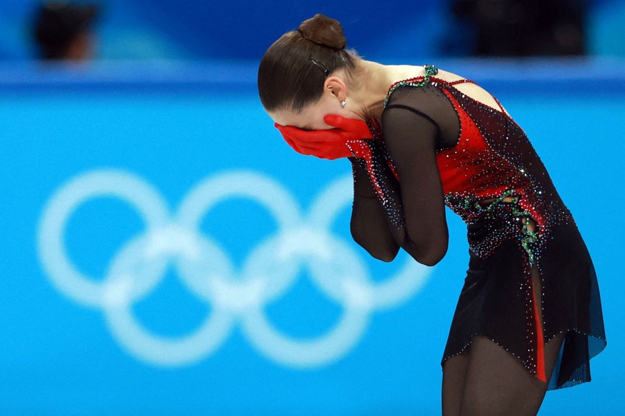A figure skater leans over, holding her face in her hands.