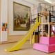 A colorful playground with a slide is placed in an old ballroom.