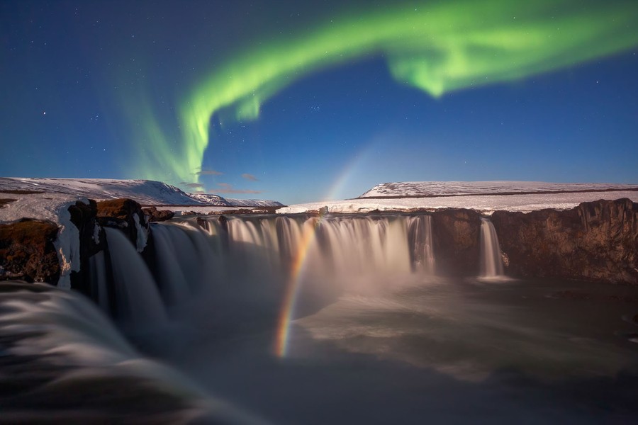 Une vue nocturne à longue exposition d'une cascade sous les aurores boréales