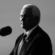 Mike Pence stands in front of a microphone, half in shadow.