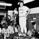 A black-and-white photo of Pete Rose addressing reporters in a locker room