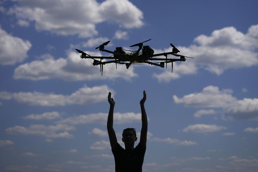 A person lifts their arms up as a drone with eight propellers lifts into the air.