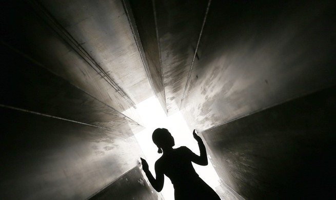 Une silhouette marchant dans un tunnel sombre et étroit vers la lumière.