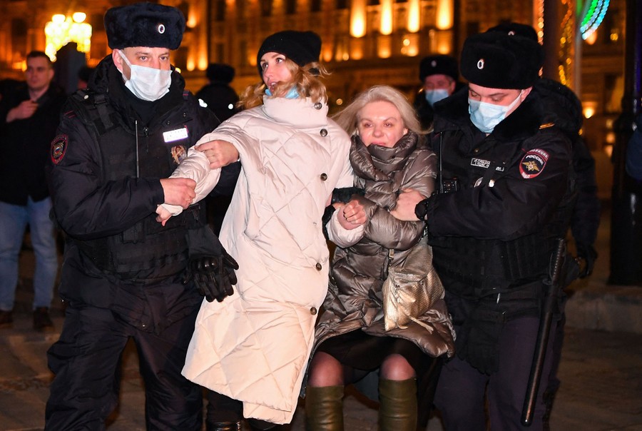 Two police officers escort two women away from an antiwar protest in Moscow.