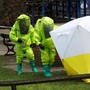 Two people in fluorescent suits approach a police tent