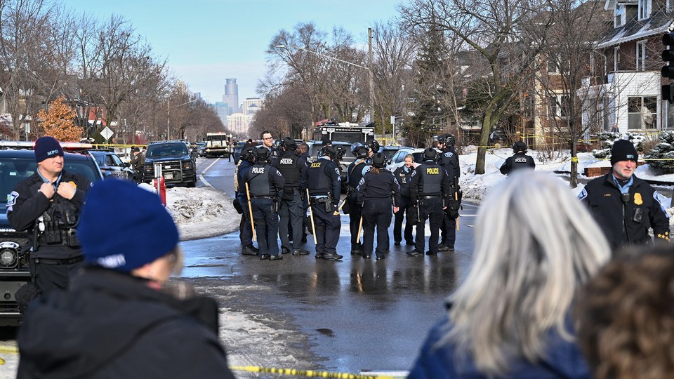 Police officers and bystanders at the scene of a shooting in Minneapolis