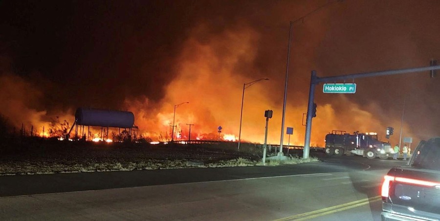 A view of a wildfire near a road intersection, seen at night