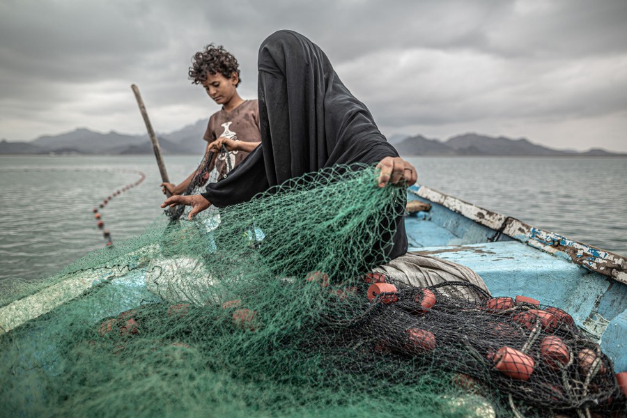 A woman and her son tend to nets in a small fishing vessel.