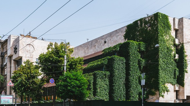 The building Flowers of Ukraine is overgrown with vegetation.