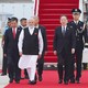 A color photo of Indian Prime Minister Narendra Modi walking on a red carpet after deplaning at a summit in China.