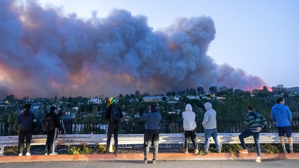 A photo of people in L.A. watching the wildfire rampaging across a hillside
