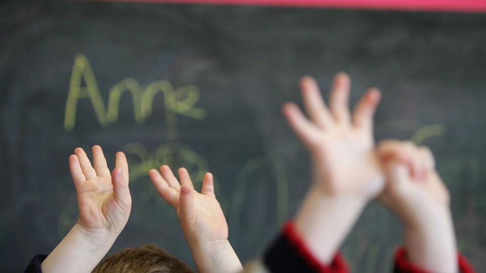 Children's hands in the air in front of a chalkboard