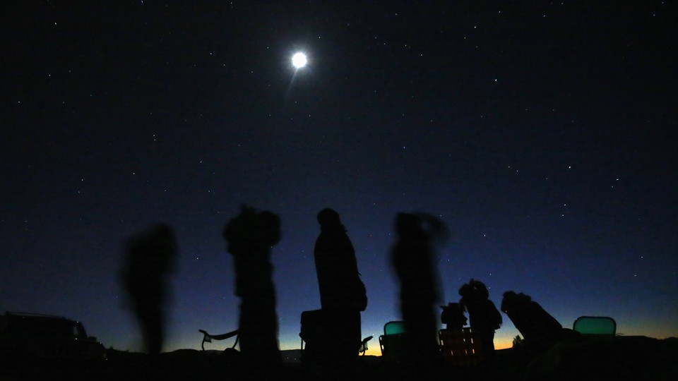 Silhouettes of stargazers against a night sky