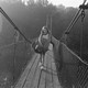 A girl carrying a sleeping bag walking over bridge
