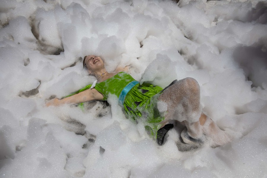 A person rolls on the ground in a huge pile of foam.