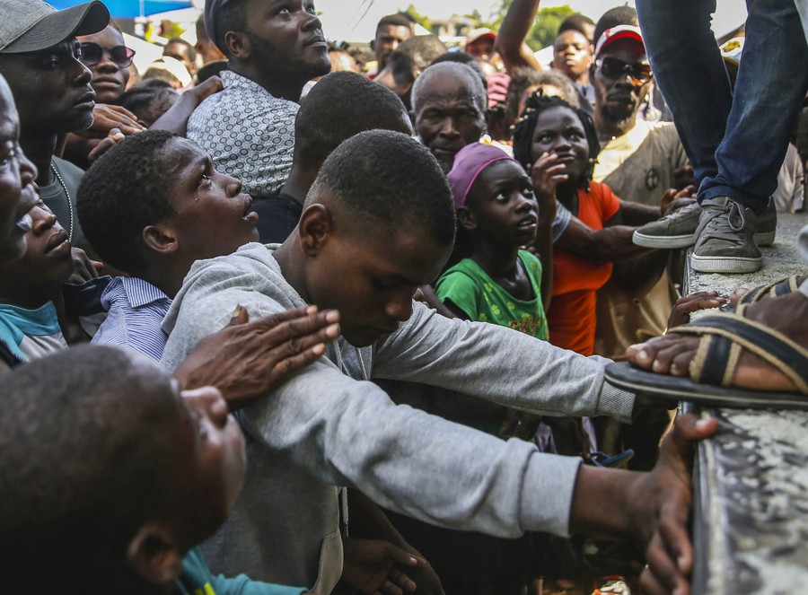 A young man cries as he waits among others for a sack of rice.