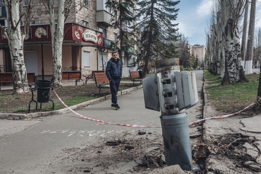A rocket stuck headfirst in a road, with a person looking on nearby.