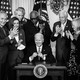 President Biden surrounded by lawmakers while signing legislation