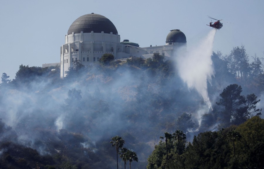 A firefighting helicopter drops water on a wildfire near the Griffith Observatory, in Los Angeles.