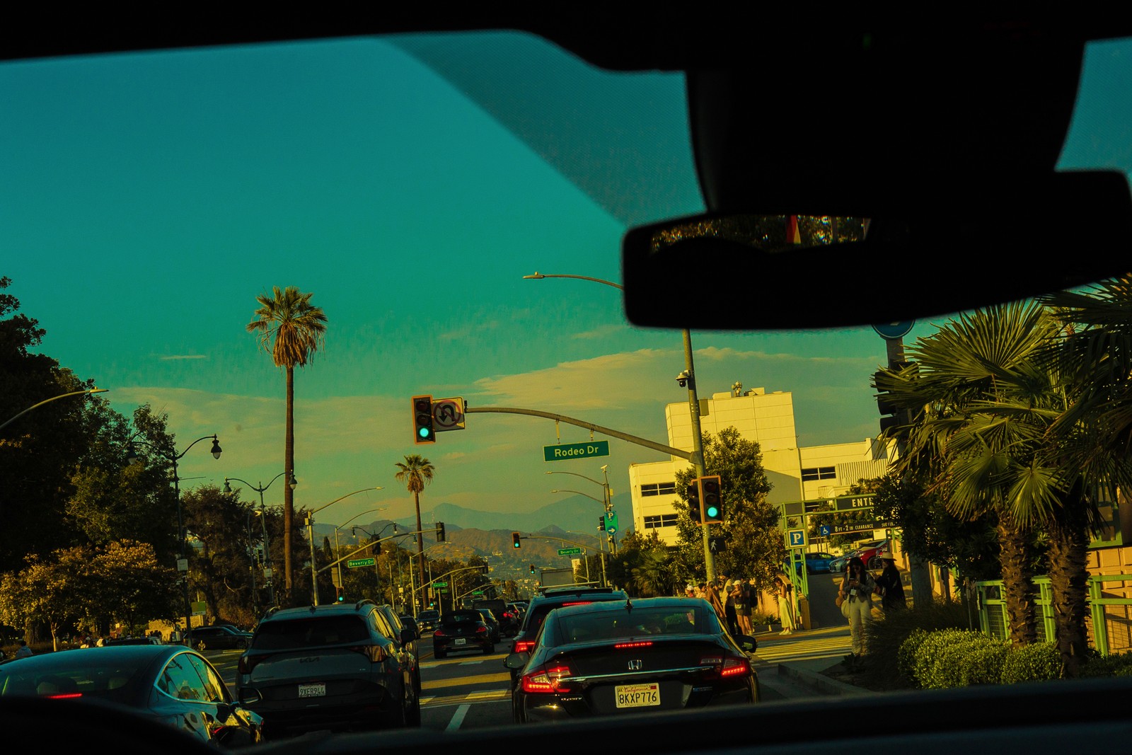 photo from interior of car of streetlight at Rodeo Drive, with palm trees and blue sky