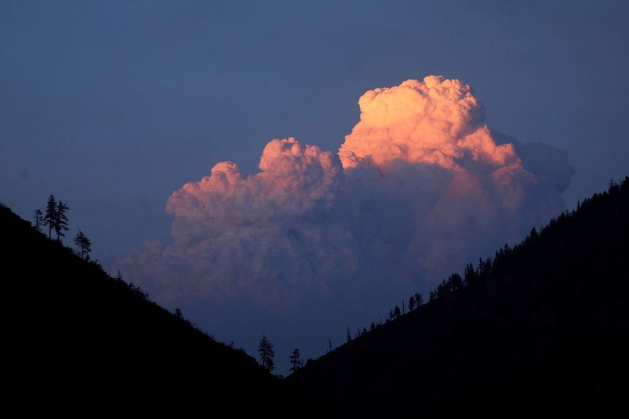 A column of smoke rises from a distant forest fire.