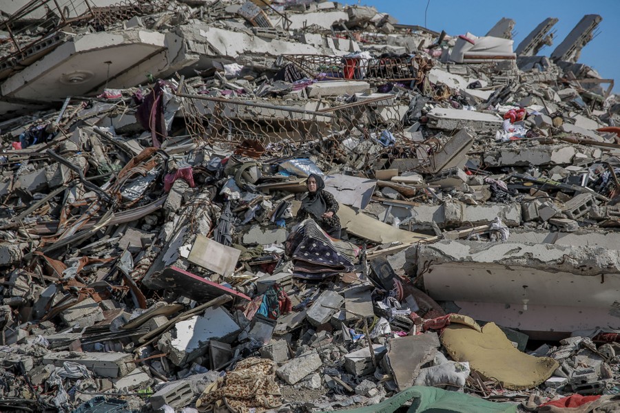 A person walks atop a giant mound of rubble from a destroyed building.