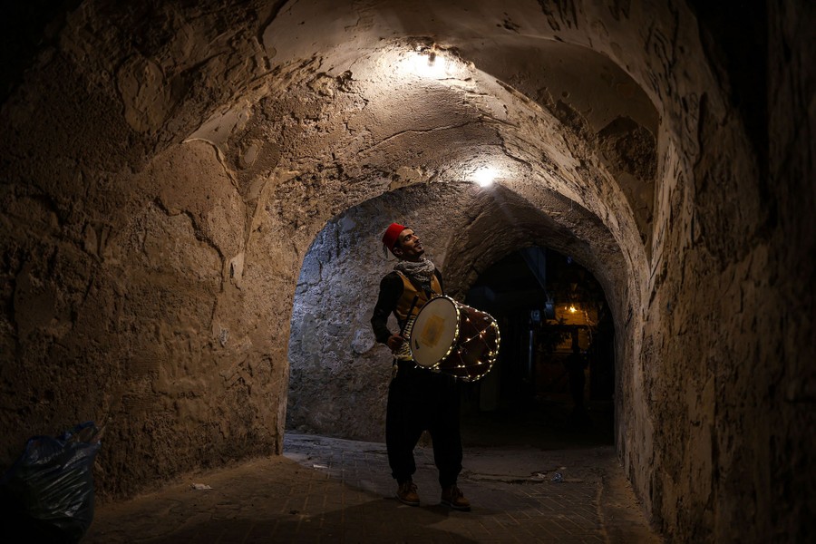 A person carries a drum while walking through a tunnel.