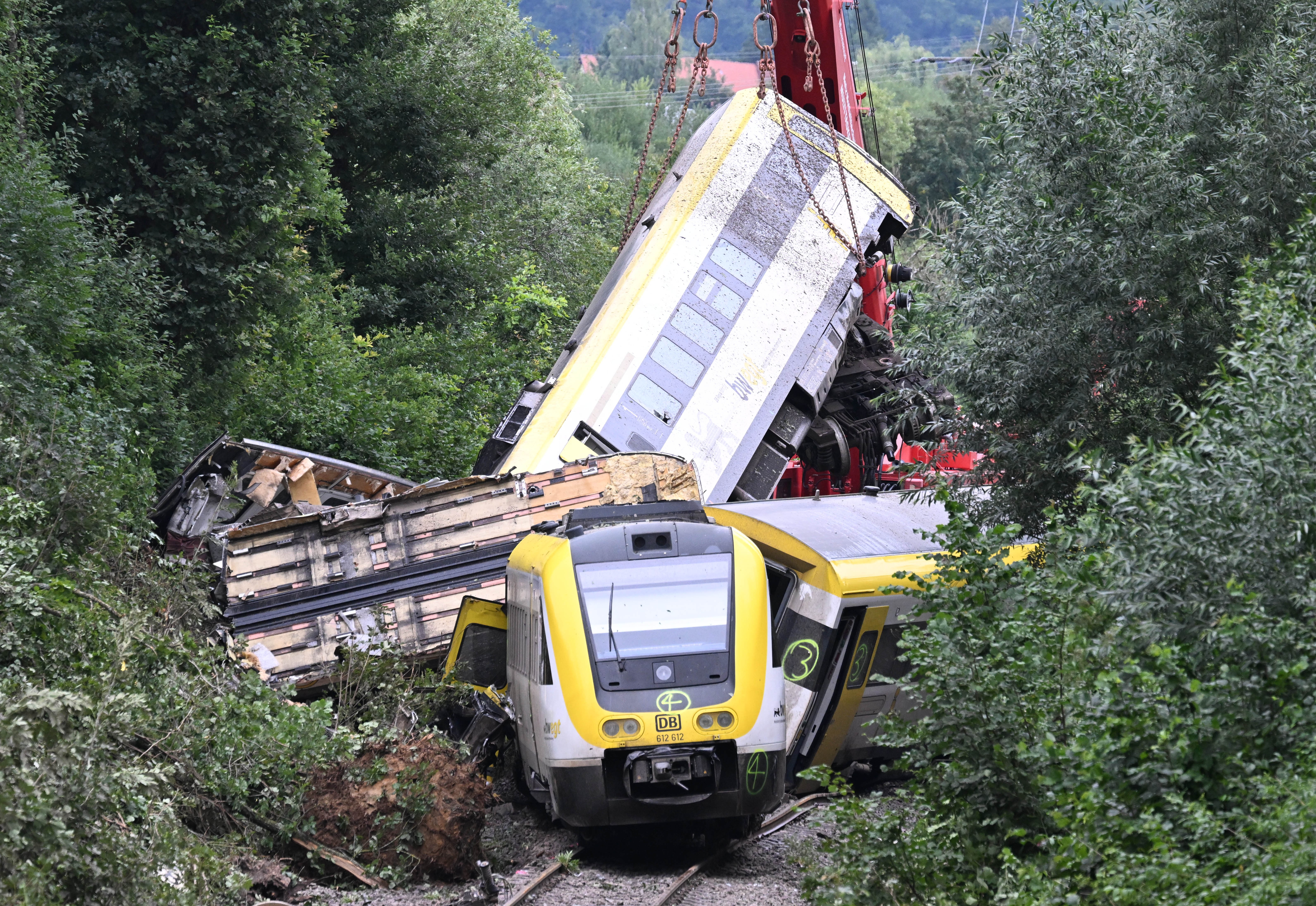 A crane works to lift a car that is part of a train wreck.