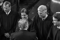 Fotografía en blanco y negro de los jueces de la Corte Suprema John Roberts, Elena Kagan, Neil Gorsuch y Brett Kavanaugh parados en una fila. Gorsuch le estrecha la mano a Donald Trump.
