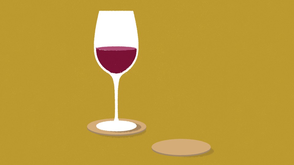 A wine glass half full with red wine on a yellow background