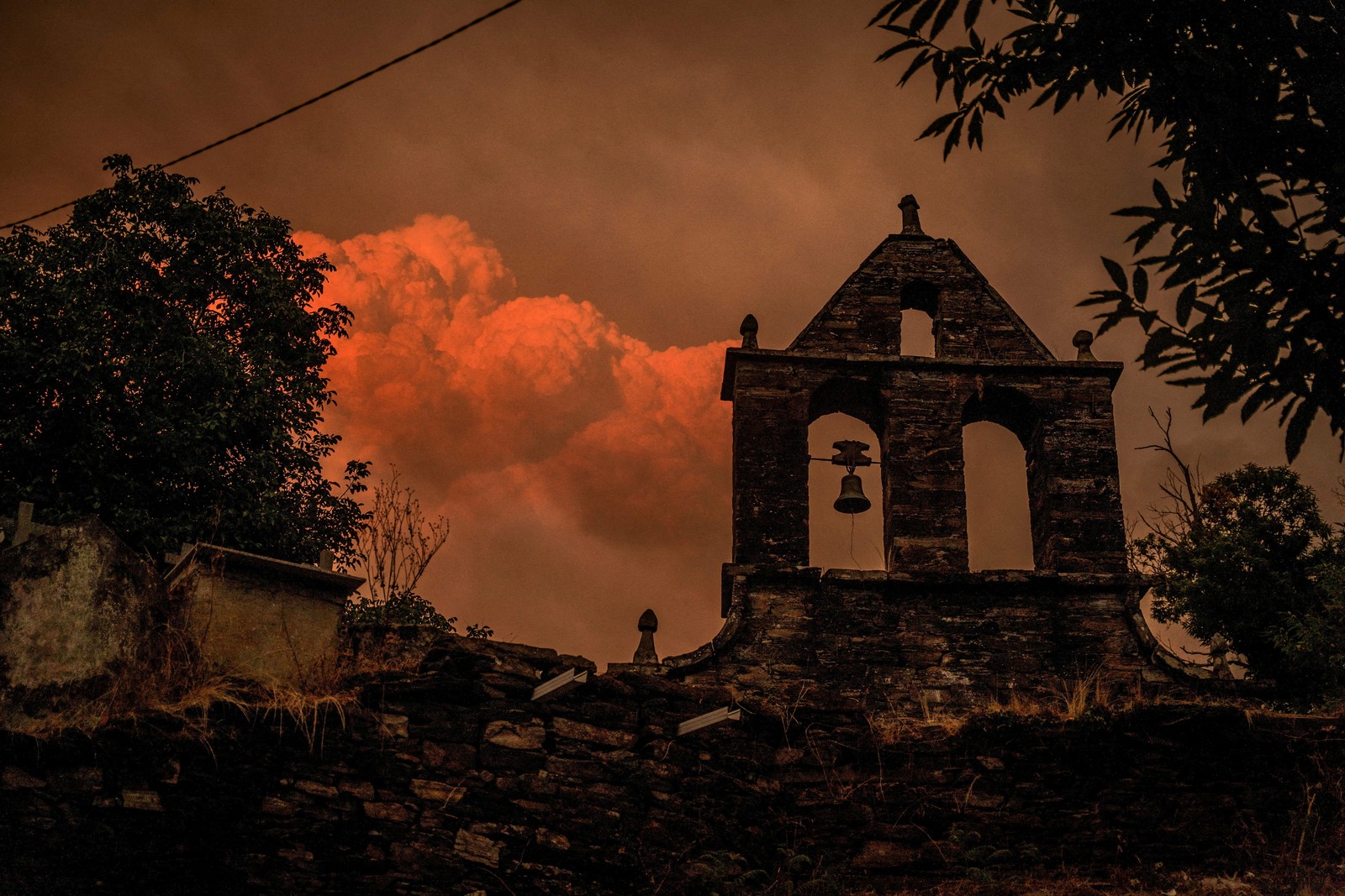 Smoke rises from a wildfire, seen beyond a cemetery in Spain.