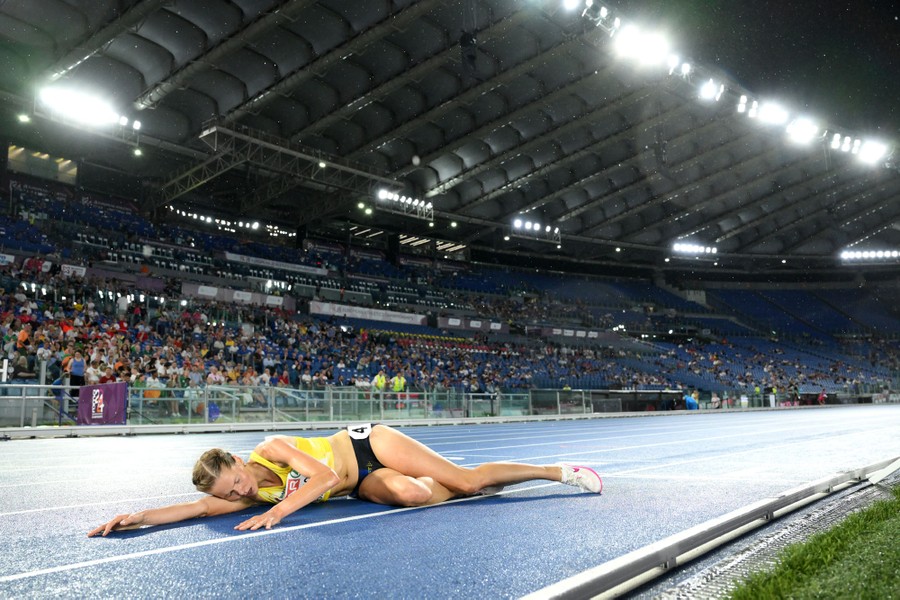 An athlete lies on the track after finishing a race.