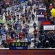 Runners approach the New York City Marathon finish line, where a clock reads 4:39:11
