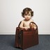 A toddler stands inside a briefcase