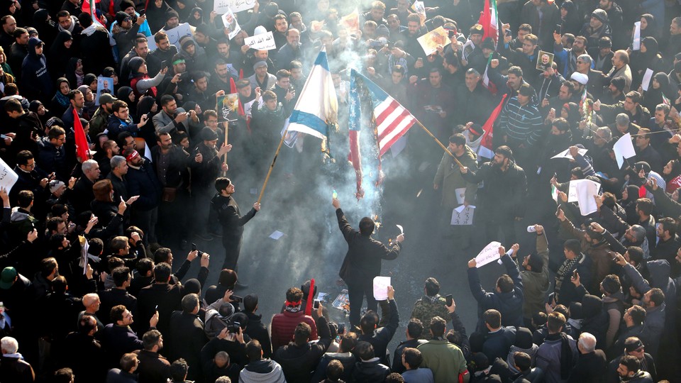 Iranians set a U.S. and an Israeli flag on fire during a funeral procession organized to mourn the slain military commander Qassem Soleimani.