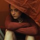 girl sitting at the opening of a tent peering out