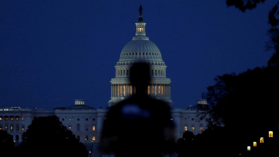 Someone walks past the U.S. Capitol building at dusk.