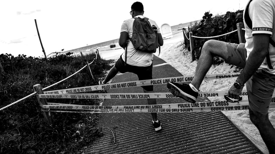 Two boys crossing police tape to gain entrance to a beach.