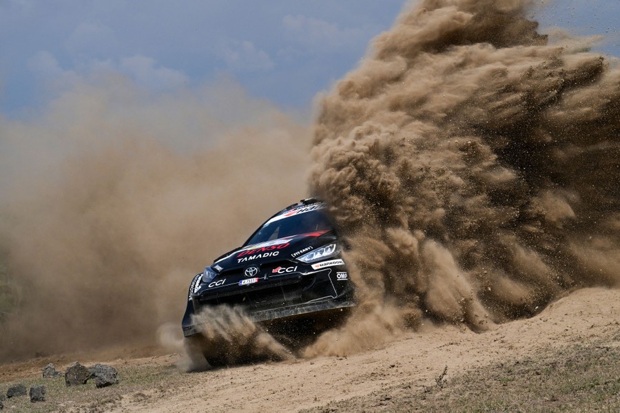 A rally car kicks up dense clouds of dust during a race.