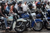 Helmeted riders sit on motorcycles