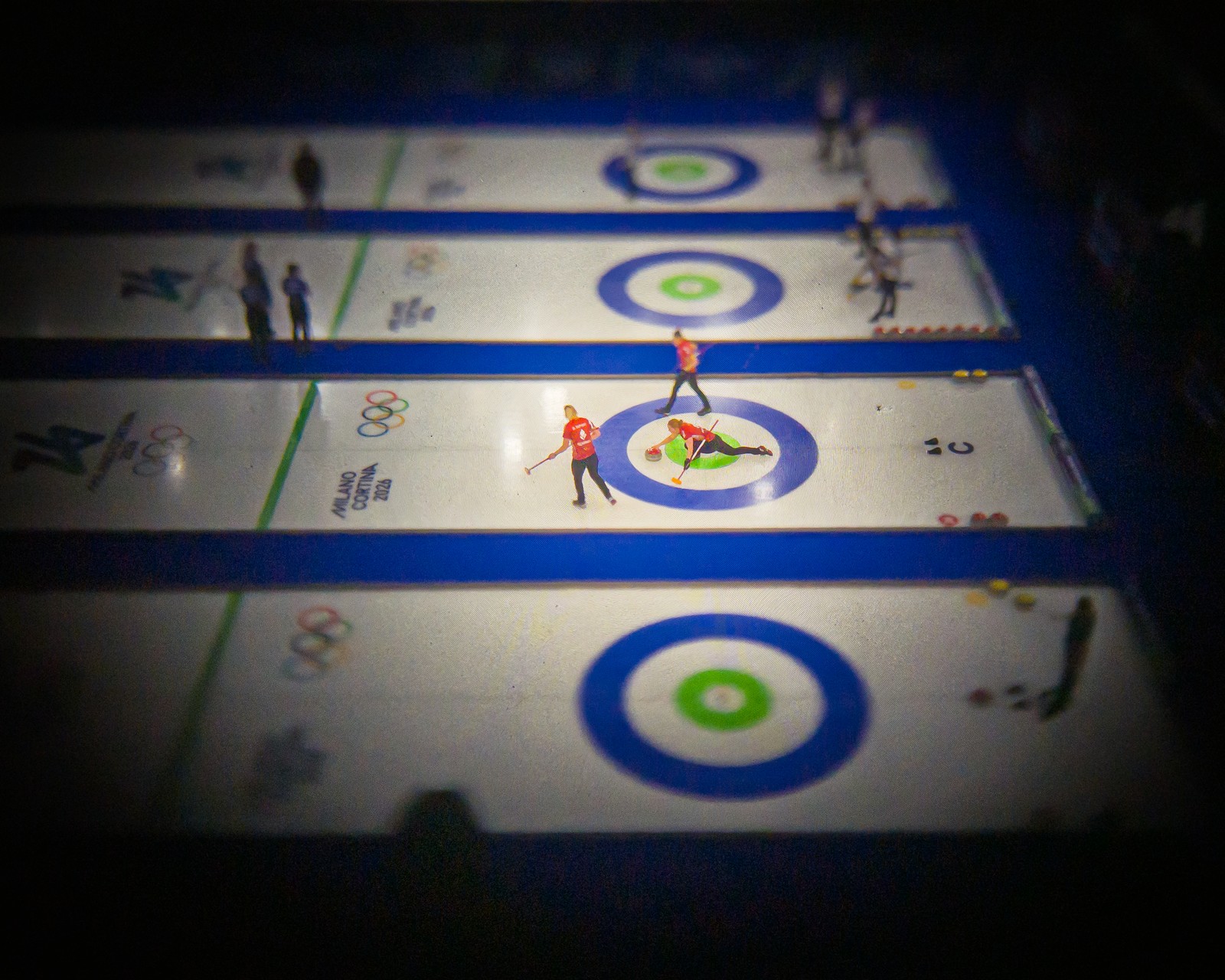 An elevated view of a curling competition, seen through an older camera lens with a dark vignette effect.