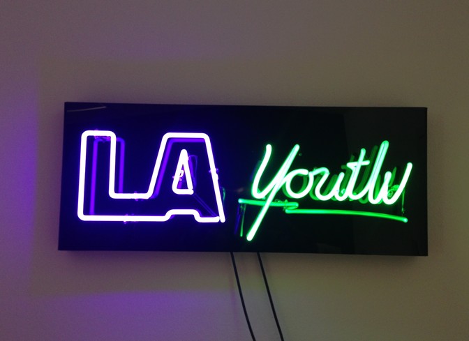 A neon sign that says "LA" in purple and "Youth" in green