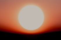 Color picture of a fuzzy white orb against an orange, red, and black background