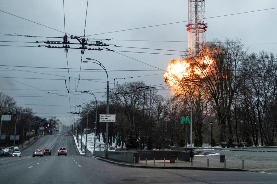 An explosion is seen in the distance around the base of a tall TV tower.