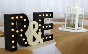 A decoration featuring a couple's initials sits on a table at a wedding reception.