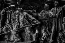 Two people walk past a large relief at the National Museum of the History of Ukraine.