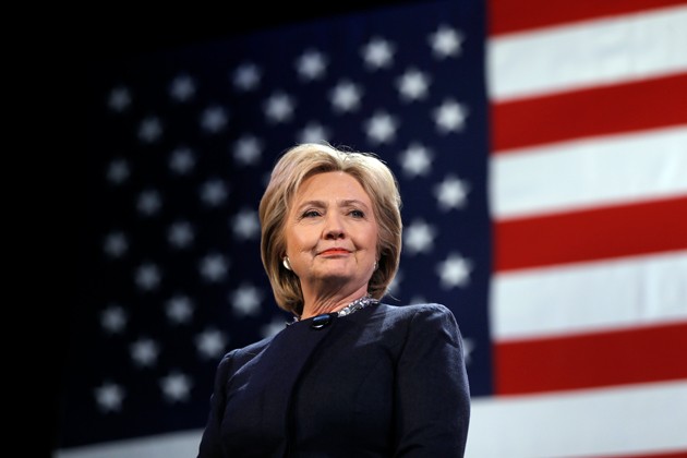Hillary Clinton standing before a huge American flag.