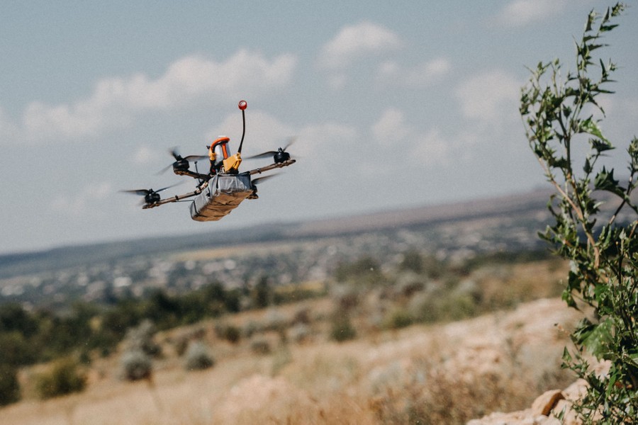 A small remote-control drone flies low over a field.