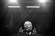 Biden speaks at a lectern with two spotlights shining on him from above.